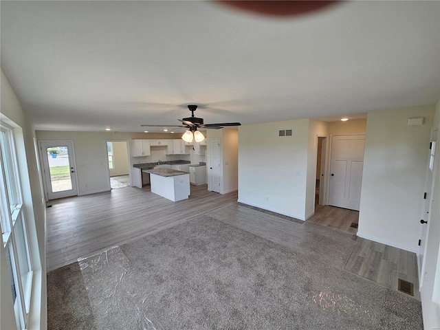 unfurnished living room with ceiling fan and wood-type flooring