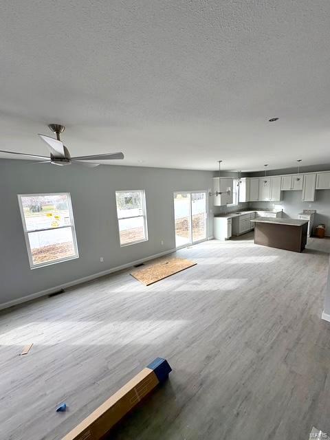 unfurnished living room with ceiling fan, hardwood / wood-style floors, and a textured ceiling