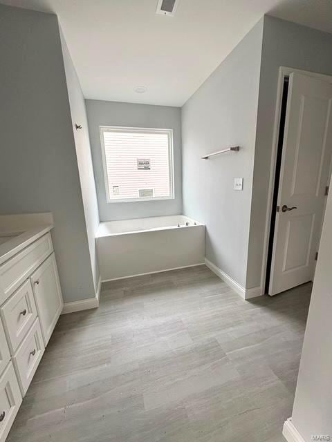 bathroom with wood-type flooring, a bath, and vanity