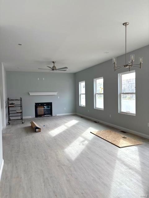 unfurnished living room with ceiling fan, plenty of natural light, and light hardwood / wood-style flooring