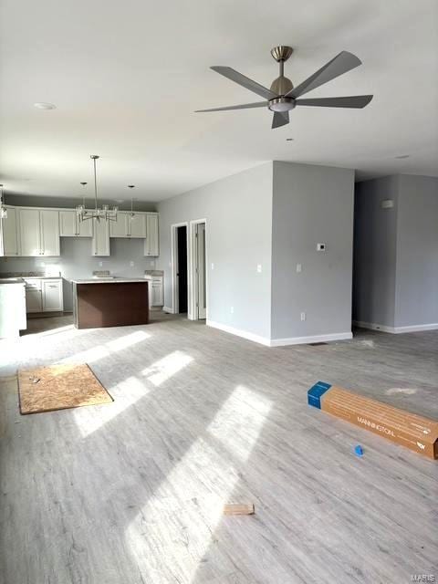 unfurnished living room featuring hardwood / wood-style flooring and ceiling fan with notable chandelier