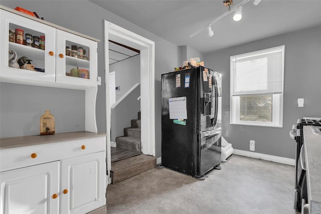 kitchen with black fridge with ice dispenser, track lighting, white cabinets, and gas range