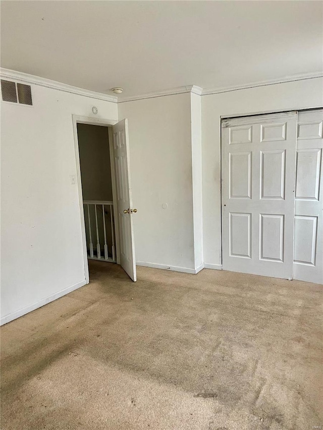 unfurnished bedroom with a closet, ornamental molding, and carpet flooring