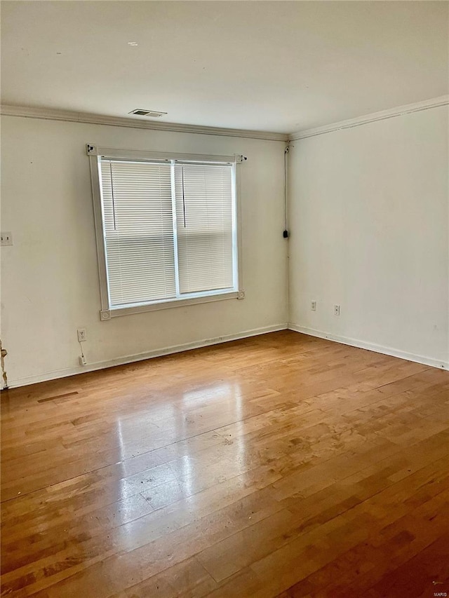 unfurnished room with ornamental molding and wood-type flooring