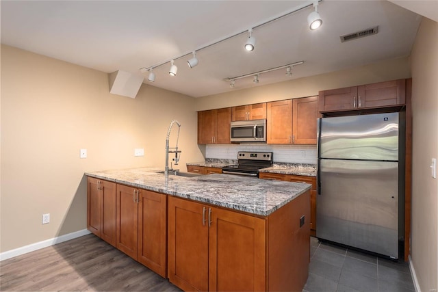 kitchen featuring stainless steel appliances, dark hardwood / wood-style floors, light stone counters, backsplash, and sink