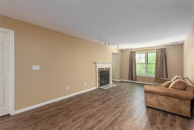 unfurnished living room with dark wood-type flooring, a tiled fireplace, and rail lighting