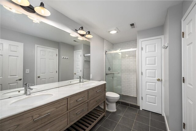 bathroom with walk in shower, double sink, tile floors, vanity with extensive cabinet space, and toilet