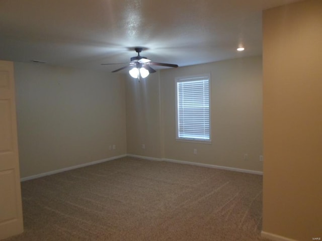 spare room featuring dark carpet and ceiling fan