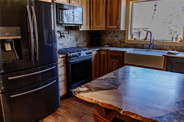 kitchen featuring sink, dark wood-type flooring, black appliances, and tasteful backsplash