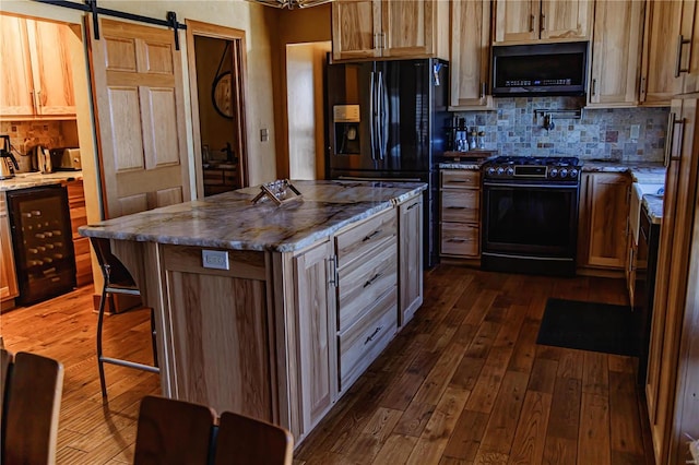 kitchen with tasteful backsplash, dark wood-type flooring, a kitchen island, a barn door, and black appliances