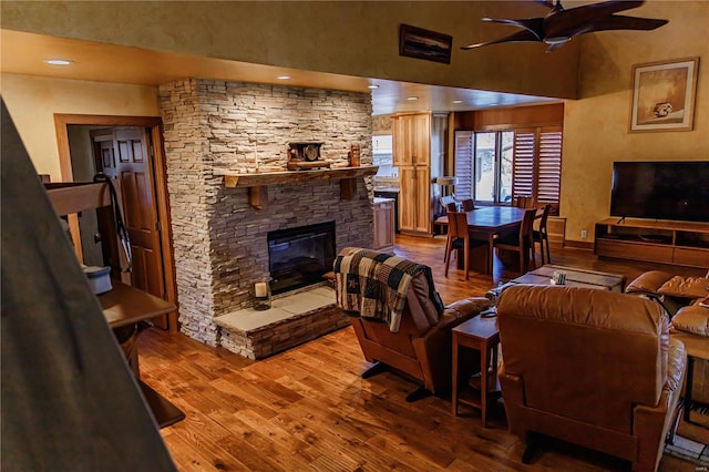 living room featuring a fireplace, ceiling fan, and wood-type flooring