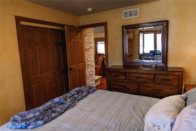 bedroom featuring multiple windows, a closet, and hardwood / wood-style floors