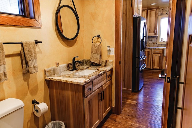 bathroom with vanity, toilet, backsplash, and hardwood / wood-style floors