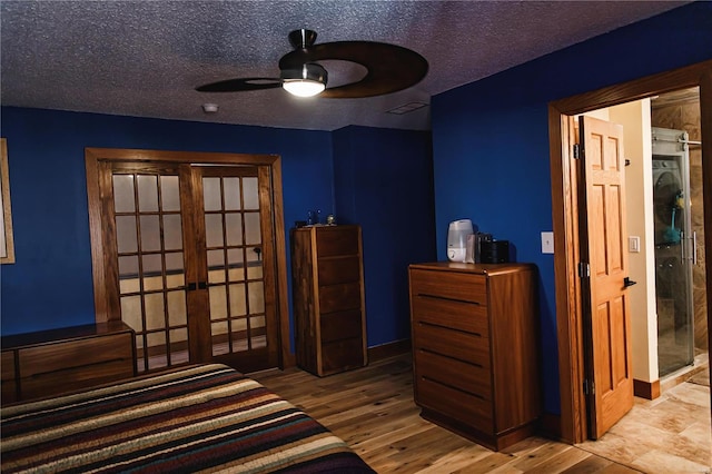 bedroom featuring light hardwood / wood-style floors, a textured ceiling, french doors, and ceiling fan