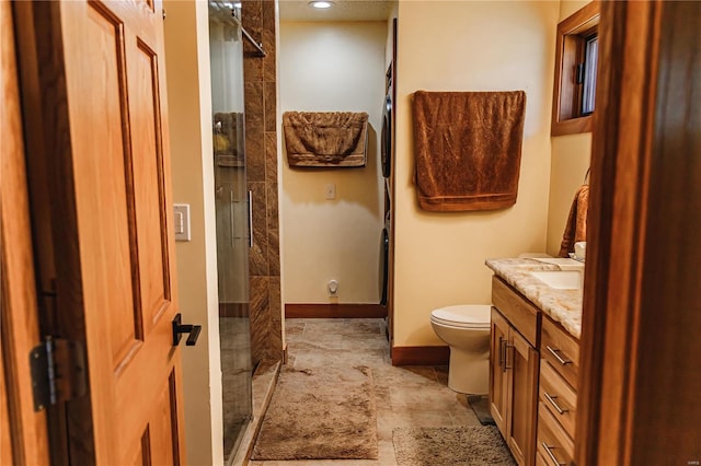 bathroom with a shower with shower door, vanity, tile patterned flooring, and toilet