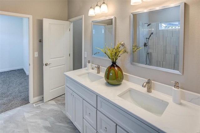 bathroom with a tile shower and vanity