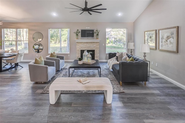 living room with high vaulted ceiling, ceiling fan, a stone fireplace, and dark hardwood / wood-style flooring