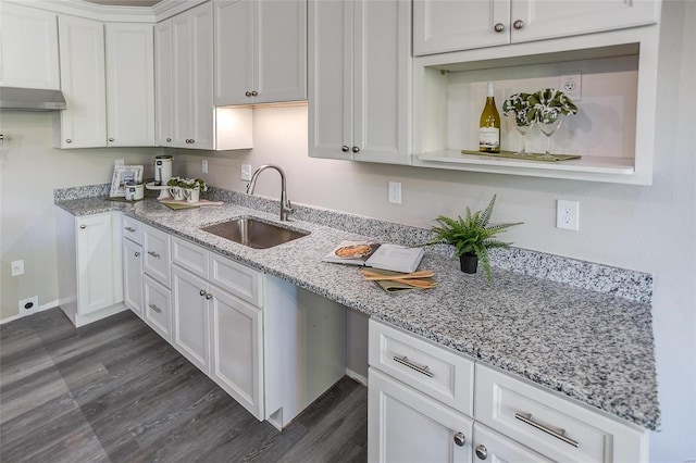 kitchen with light stone countertops, white cabinets, sink, and dark hardwood / wood-style flooring