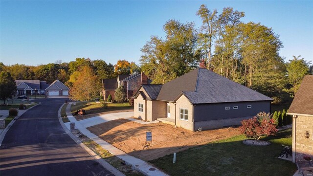 view of front of house with a residential view, brick siding, and a detached garage