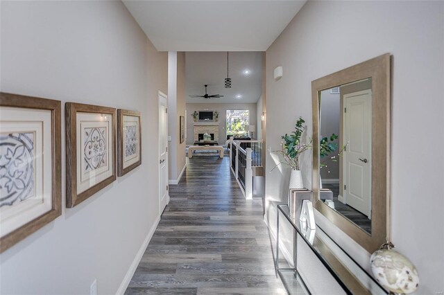 hallway with dark wood finished floors, a towering ceiling, and baseboards