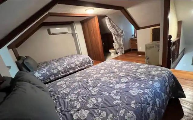 bedroom featuring a wall mounted air conditioner, vaulted ceiling, and wood-type flooring