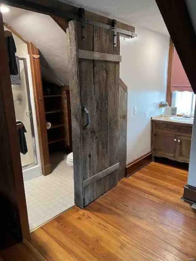 bonus room featuring light wood-type flooring and a barn door