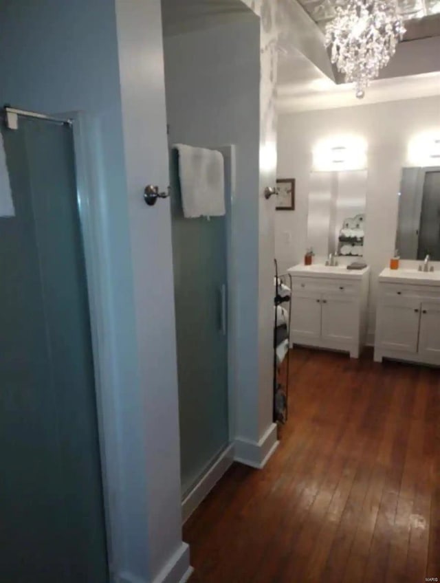 bathroom with a shower with shower door, a notable chandelier, vanity, and wood-type flooring