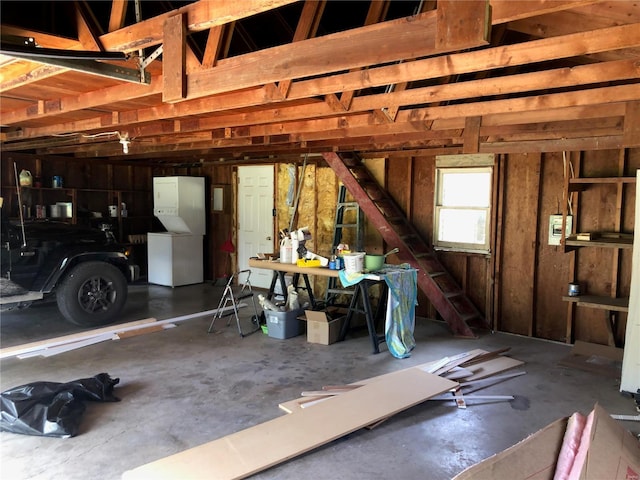 garage featuring white refrigerator and stacked washer / dryer