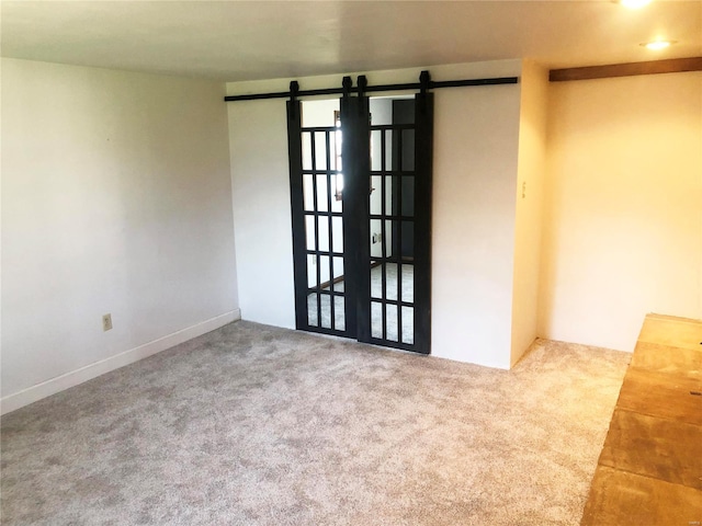 carpeted spare room with a barn door