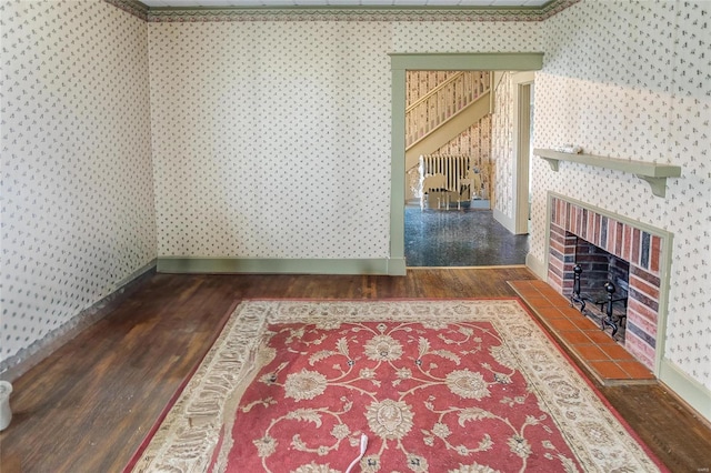 interior space featuring radiator, a brick fireplace, and dark wood-type flooring