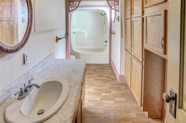 full bathroom featuring toilet, tub / shower combination, vanity, tasteful backsplash, and wood-type flooring