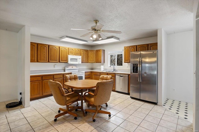 kitchen featuring sink, light tile patterned floors, a textured ceiling, and appliances with stainless steel finishes