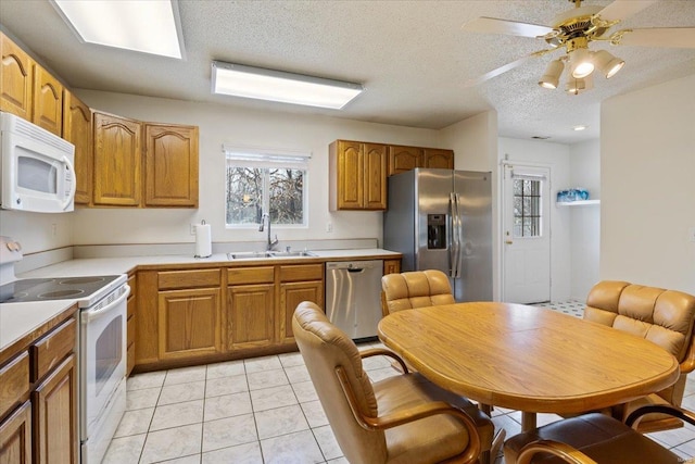 kitchen with sink, ceiling fan, light tile patterned floors, a textured ceiling, and stainless steel appliances