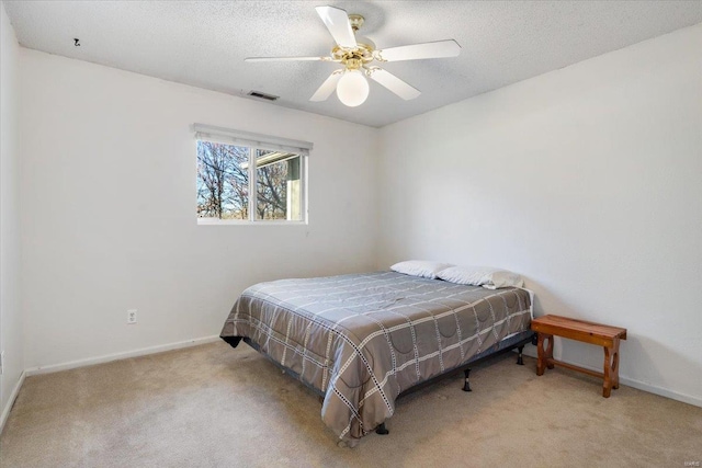 bedroom with ceiling fan, light colored carpet, and a textured ceiling