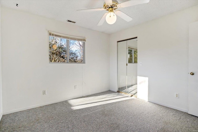 spare room featuring ceiling fan, plenty of natural light, carpet, and a textured ceiling