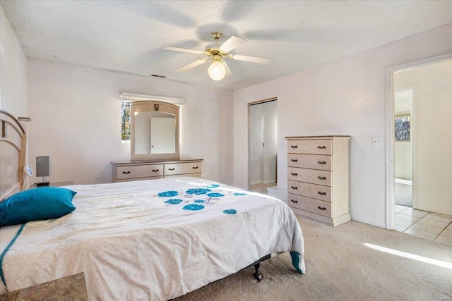 carpeted bedroom with ceiling fan, a closet, and a textured ceiling