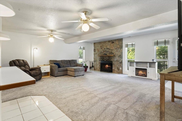 carpeted living room with a textured ceiling, a stone fireplace, and ceiling fan