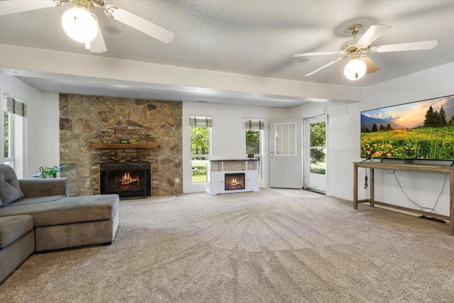 carpeted living room featuring ceiling fan, a fireplace, and a textured ceiling