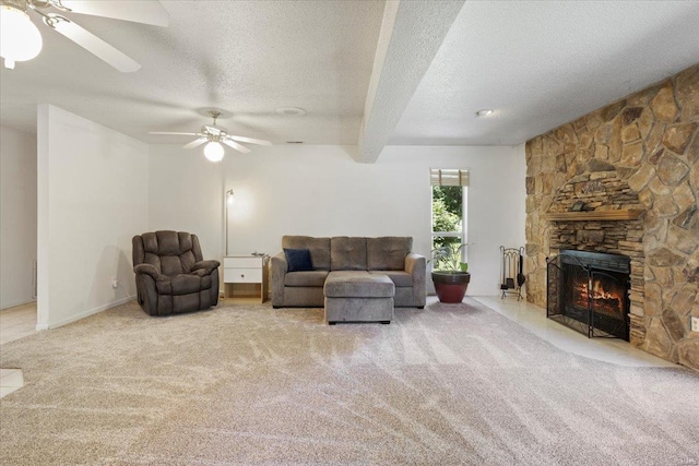 carpeted living room with a textured ceiling, a stone fireplace, and ceiling fan