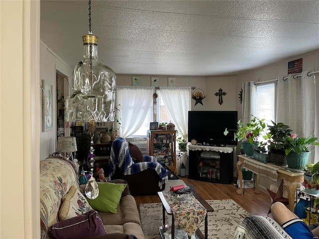 living room featuring a textured ceiling, a notable chandelier, and wood-type flooring