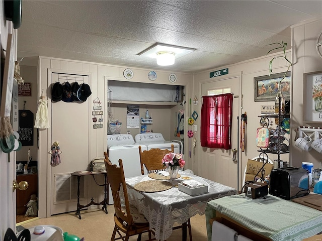 dining area featuring washing machine and dryer, light carpet, and a textured ceiling