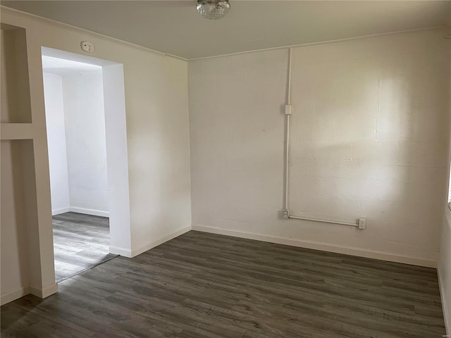 empty room featuring dark wood-type flooring and crown molding