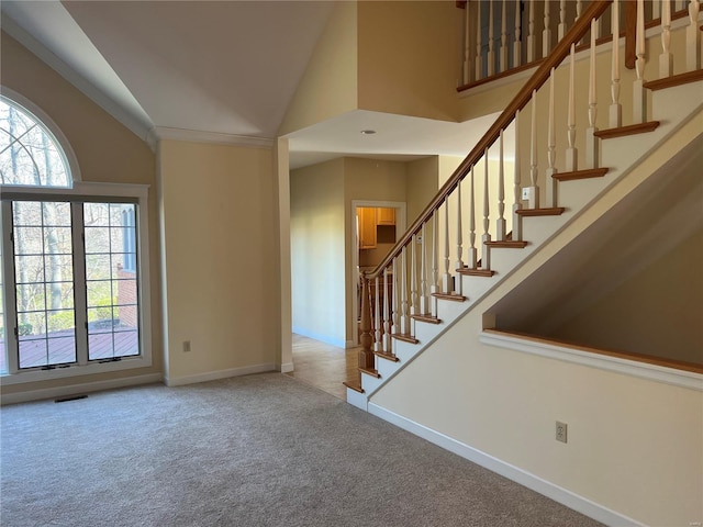 carpeted foyer entrance featuring high vaulted ceiling