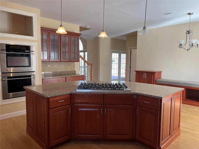 kitchen featuring a notable chandelier, decorative light fixtures, a kitchen island, and appliances with stainless steel finishes