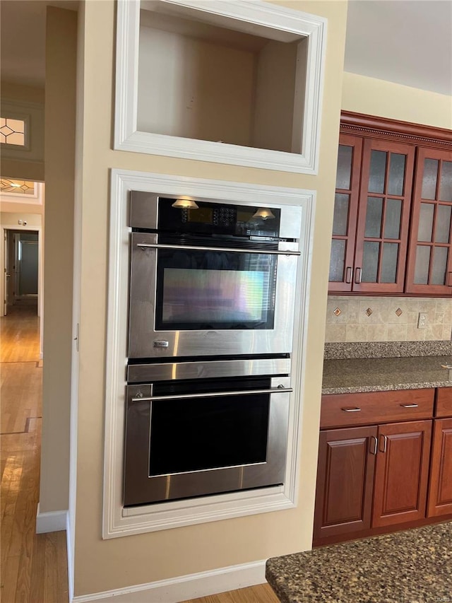 kitchen with backsplash, light wood-type flooring, and multiple ovens