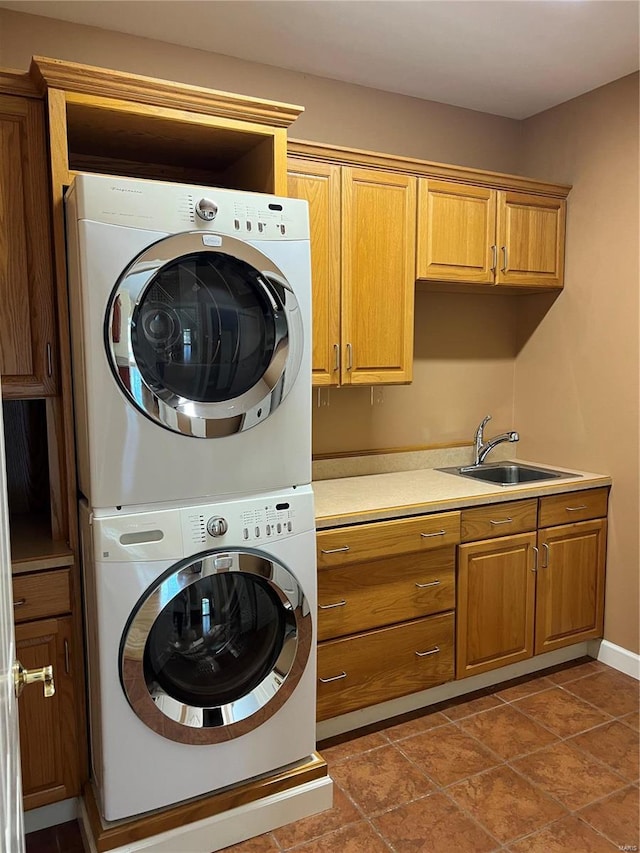 clothes washing area featuring stacked washer / dryer, tile floors, cabinets, and sink