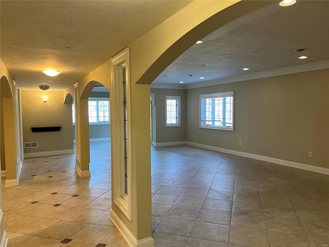 tiled empty room featuring crown molding and a healthy amount of sunlight