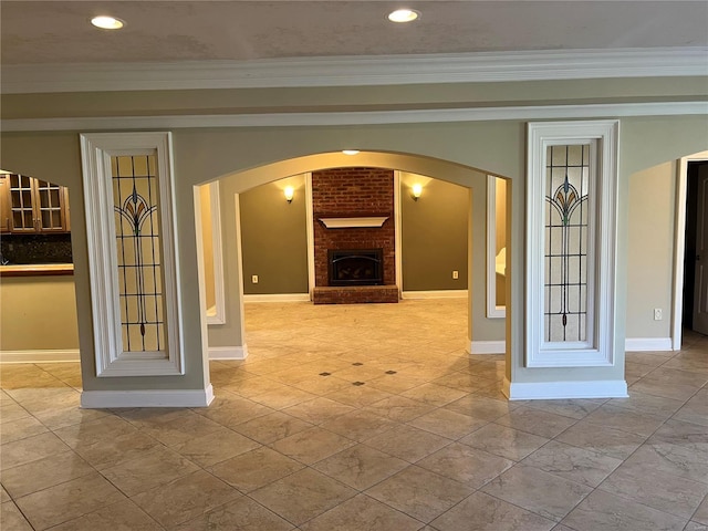 tiled empty room featuring brick wall, crown molding, and a fireplace