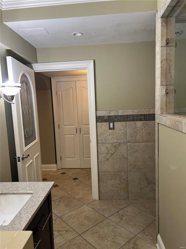 bathroom featuring tile flooring, a tile shower, and vanity