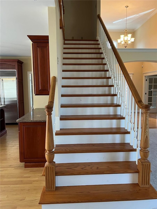 stairs with light hardwood / wood-style flooring and an inviting chandelier